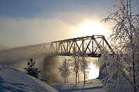 Järnvägsbron i Vaalankurkku insvept i dimma som stiger från Uleälven.