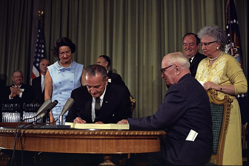 Fil:Lyndon Johnson signing Medicare bill, with Harry Truman, 30 July, 1965.jpg