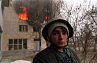 Tjetjensk pojke i skyddshjälm framför ett brinnande hus under det första Tjetjenienkriget.
