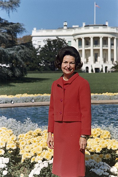 Fil:Lady Bird Johnson, photo portrait, standing at rear of White House, color.jpg