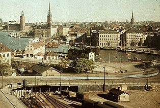 En blick över Slussen före och efter att Slussens trafikkarussell byggdes visar stora förändringar i stadslandskapet. Trafiken på vattnet, på järnvägsspår och på land möttes vid Slussen och skapade "slusselendet". Problemet löstes med invigningen av nya Slussen 1935. Sedan dess har även Centralbron och tunnelbanan förändrat stadsbilden. Bilden till vänster är från 1928, bilden till höger från 2005, vy mot nordväst med Gamla stan i bakgrunden, Stockholms stadshus till vänster och Riddarholmskyrkans torn närmast mitten. Fotografiet från 1928 togs av Gustaf W. Cronquist.